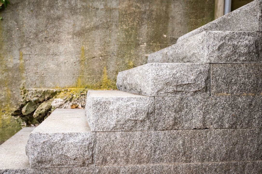 Stone steps leading up alongside a textured wall with moss, creating a rustic, weathered look. No people or landmarks visible.